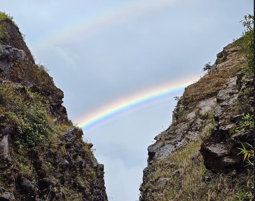 Rainbow appearing between a gap in two rocky hillsides